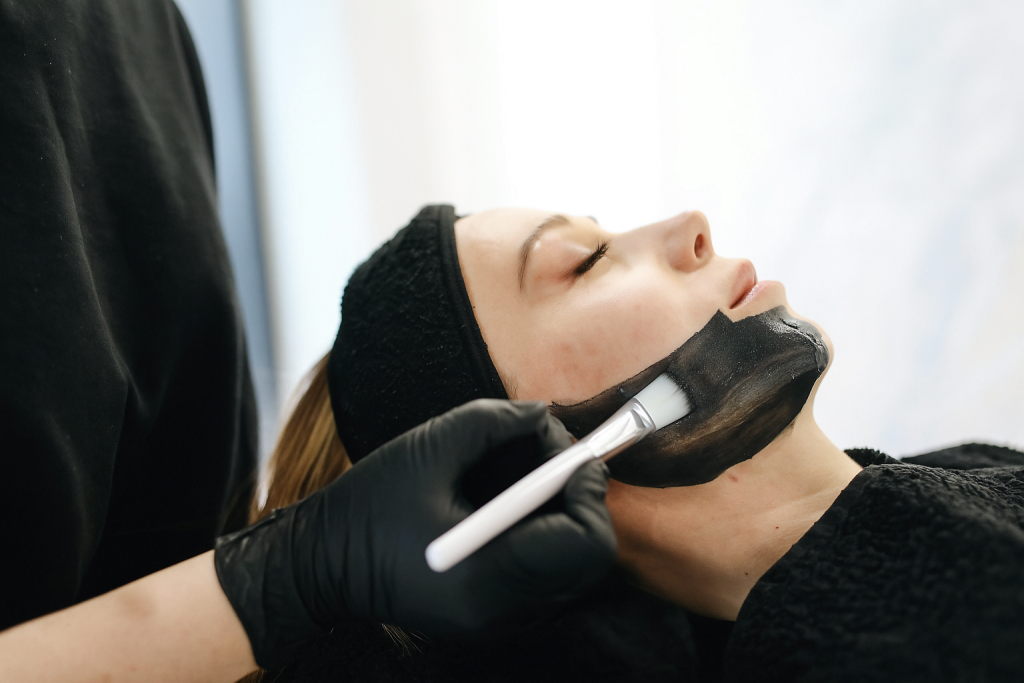 Close-up of a woman enjoying a relaxing charcoal facial treatment in a spa.